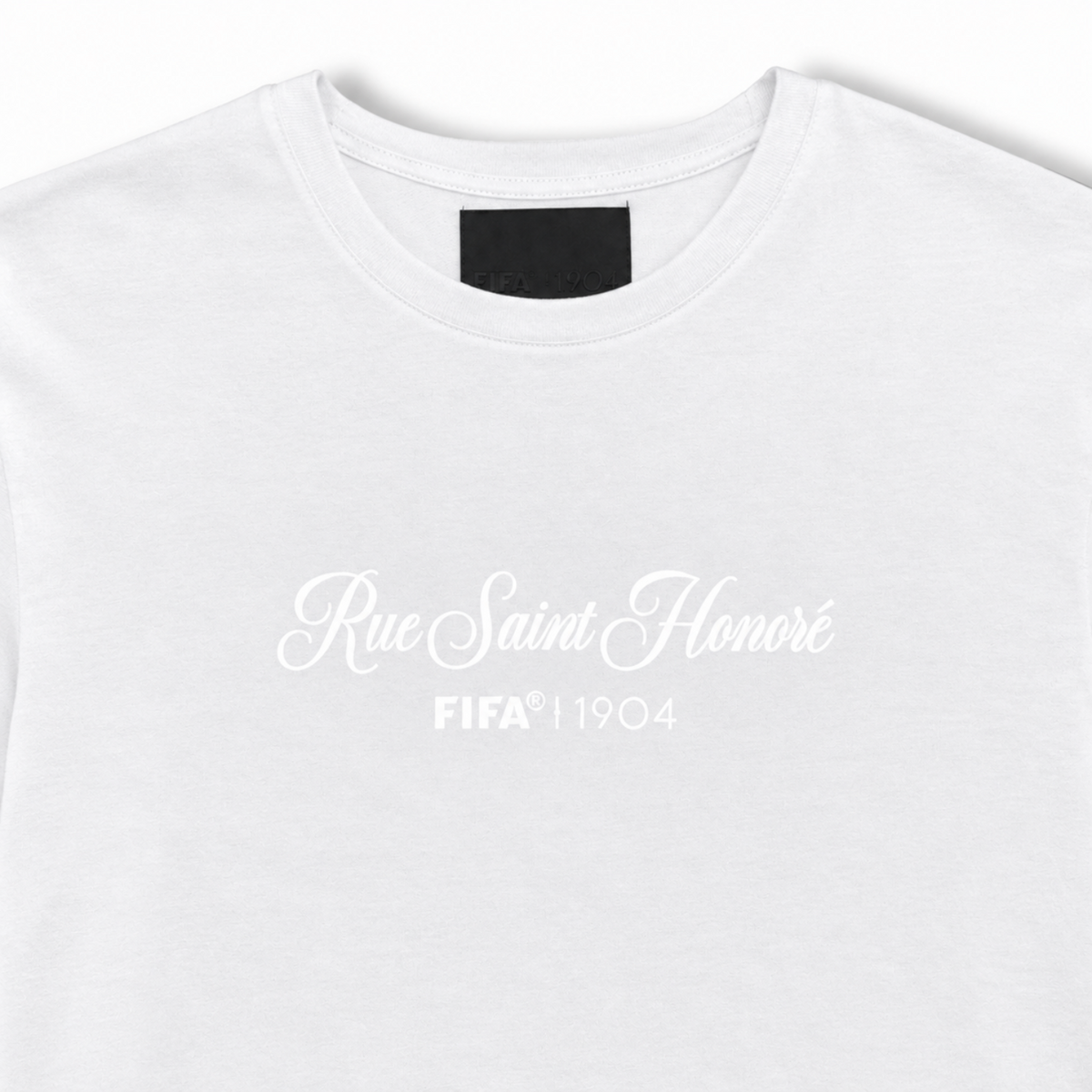 A close-up of a white crewneck t-shirt featuring the text 'Rue Saint Honoré FIFA 1904' printed in white on the chest.