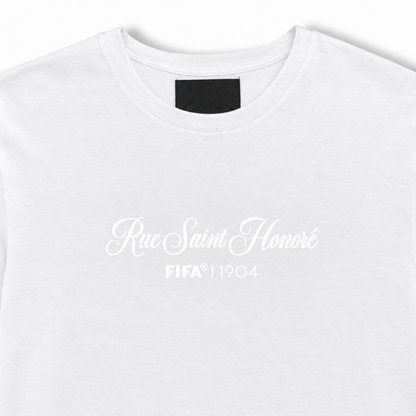 A close-up of a white crewneck t-shirt featuring the text 'Rue Saint Honoré FIFA 1904' printed in white on the chest.